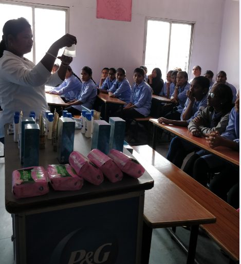 A P&G hygiene session in a classroom, with sanitary products on the front desk